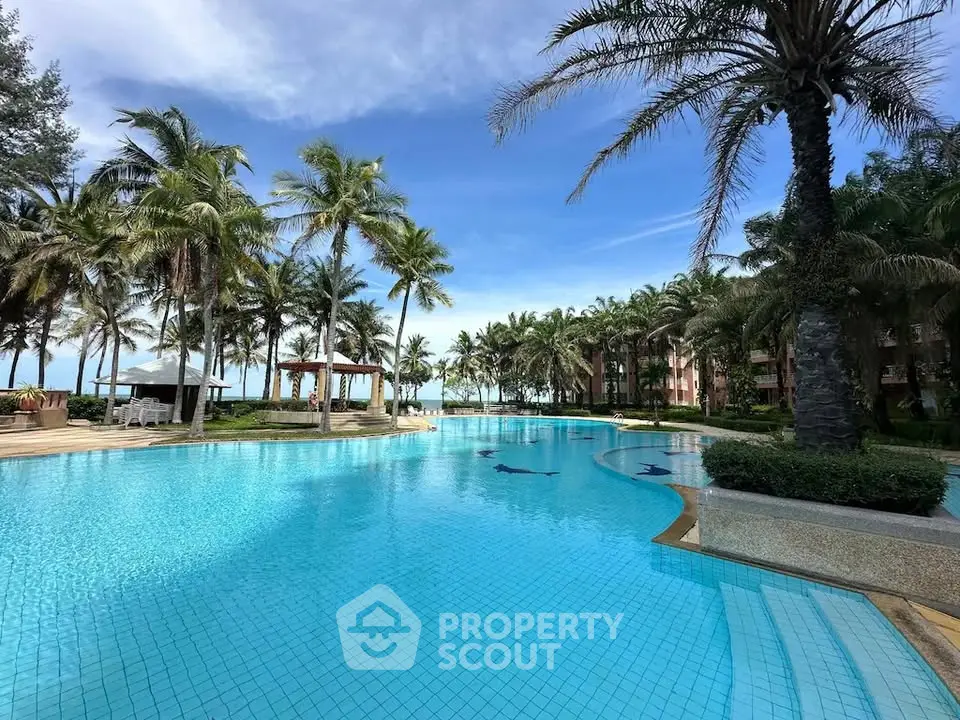 Luxurious resort-style pool with palm trees and ocean view, perfect for relaxation.