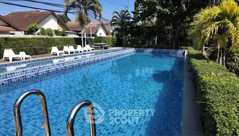 Luxurious outdoor pool area with lush greenery and sun loungers in a serene residential setting.