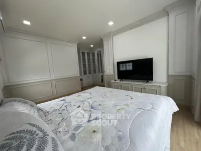 Spacious bedroom with elegant decor and large TV, perfect for relaxation.