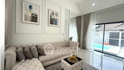 Luxurious living room with elegant decor and pool view, featuring plush seating and modern art.