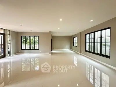 Spacious modern living room with large windows and glossy floors, perfect for natural light and open living.