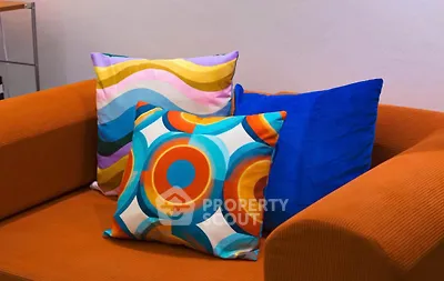 Stylish living room with vibrant cushions on an orange sofa, perfect for modern interiors.