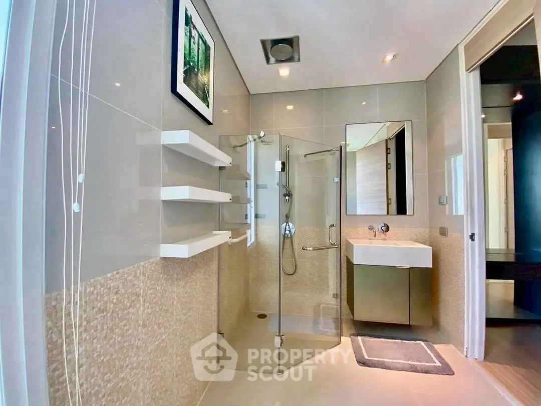 Modern bathroom with glass shower and sleek vanity in luxury apartment.