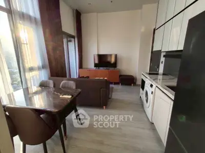 Modern living room with open kitchen, featuring sleek furniture and natural light.