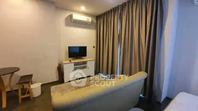 Cozy living room with modern sofa, TV, and air conditioning, perfect for relaxation.
