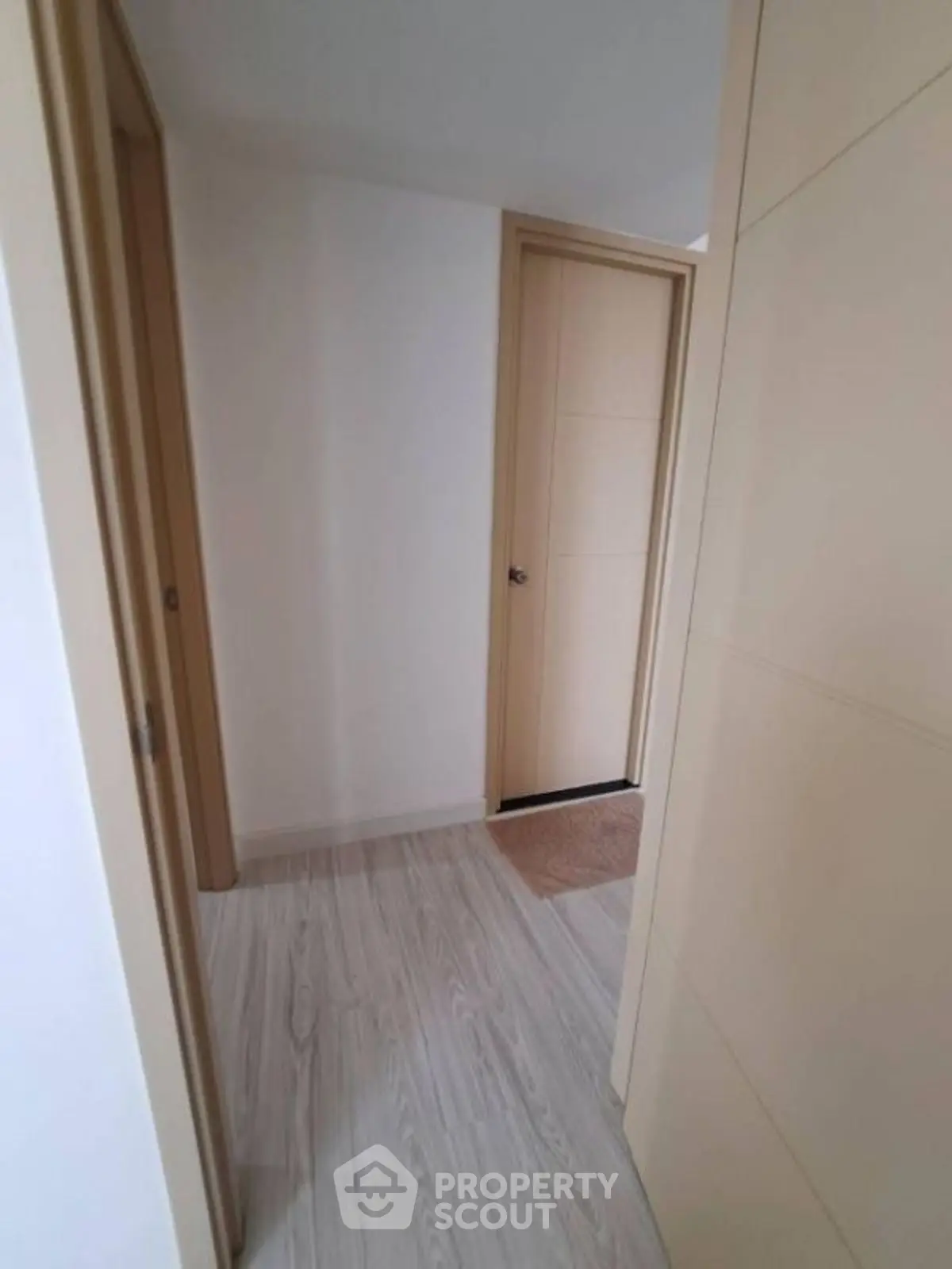 Modern hallway with light wood flooring and beige doors in a contemporary home.