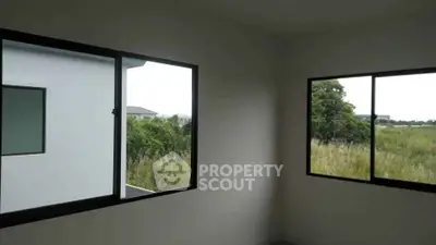 Bright room with large windows offering lush green views, perfect for a serene living space.