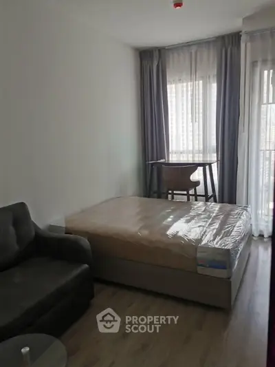 Cozy studio apartment with bed, sofa, and balcony access, perfect for urban living.