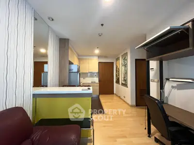 Modern open-layout living space with kitchen and study area, featuring sleek design and ample lighting.