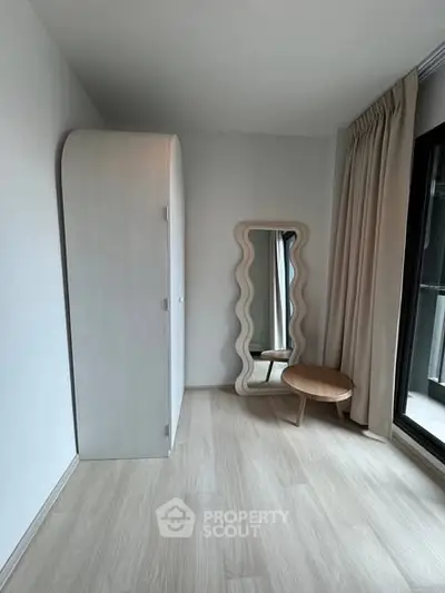 Minimalist bedroom with unique mirror and wardrobe, featuring floor-to-ceiling window.