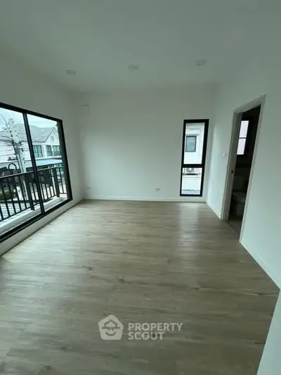 Spacious empty room with large windows and balcony access in modern home.