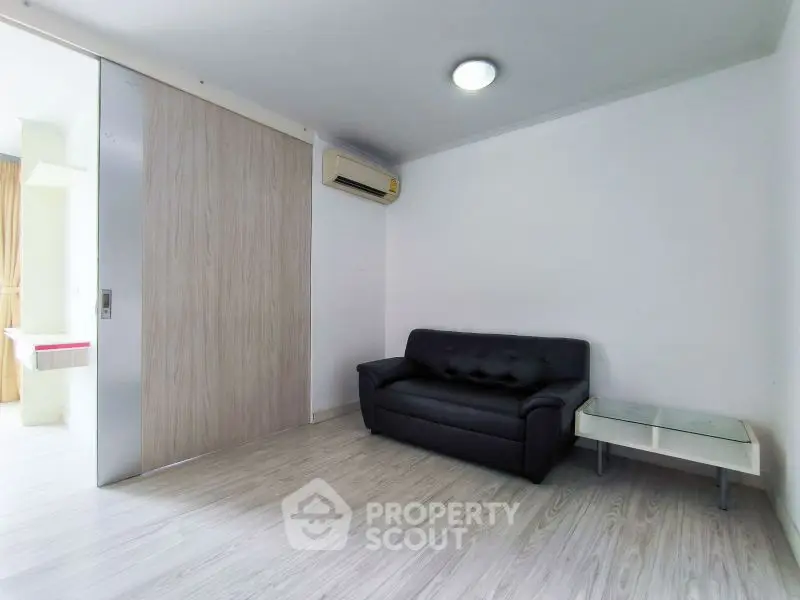 Modern living room with sleek black sofa and sliding wooden door