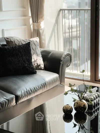 Elegant living room with leather sofa and chic decor, featuring a sunlit balcony view.