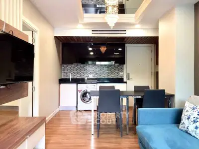 Modern living room with open kitchen, washing machine, and elegant chandelier.