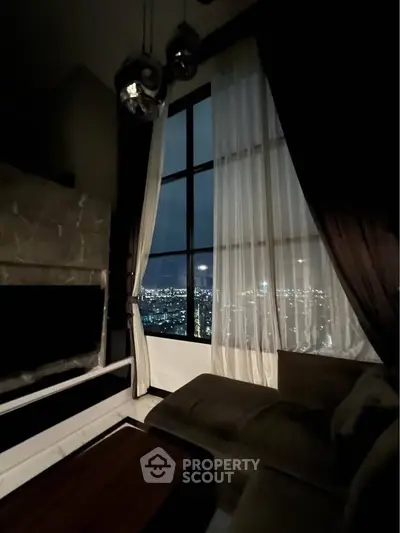 Luxurious living room with stunning city view through large windows at night.