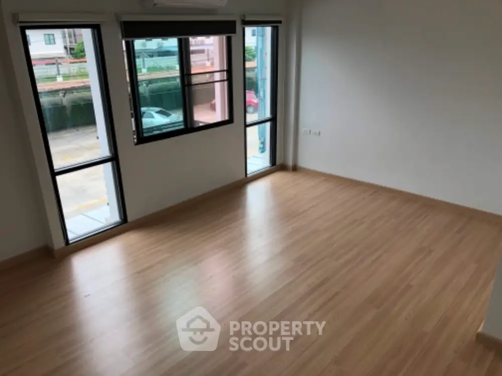 Spacious empty room with large windows and wooden flooring, ideal for customization.