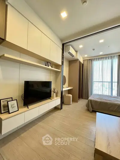 Modern bedroom with TV and stylish decor, featuring natural light and elegant furnishings.