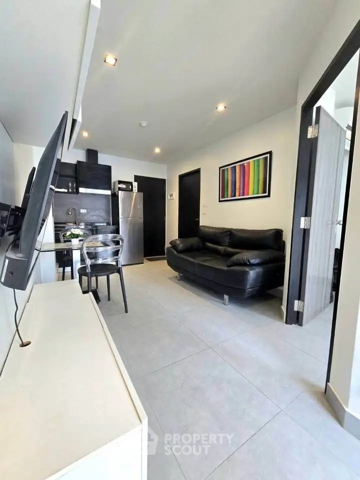 Modern living room with sleek black furniture and open kitchen layout in a stylish apartment.
