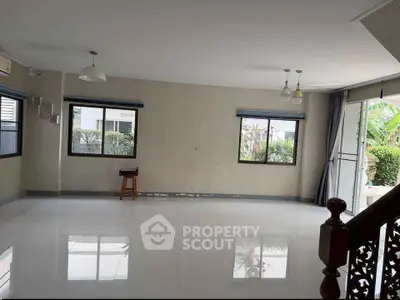 Spacious living room with large windows and garden view, perfect for family gatherings.