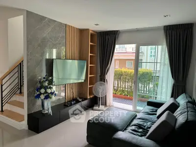 Modern living room with sleek design, large TV, and garden view through glass doors.