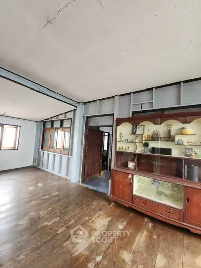 Spacious vintage living room with wooden floors and classic display cabinet