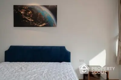 Modern bedroom with stylish blue headboard and earth-themed wall art