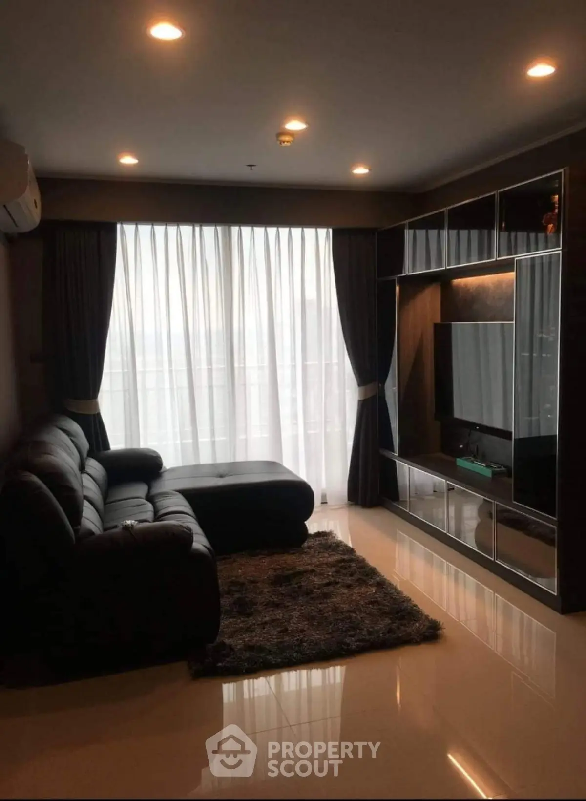 Modern living room with sleek furniture and large window, perfect for relaxation.