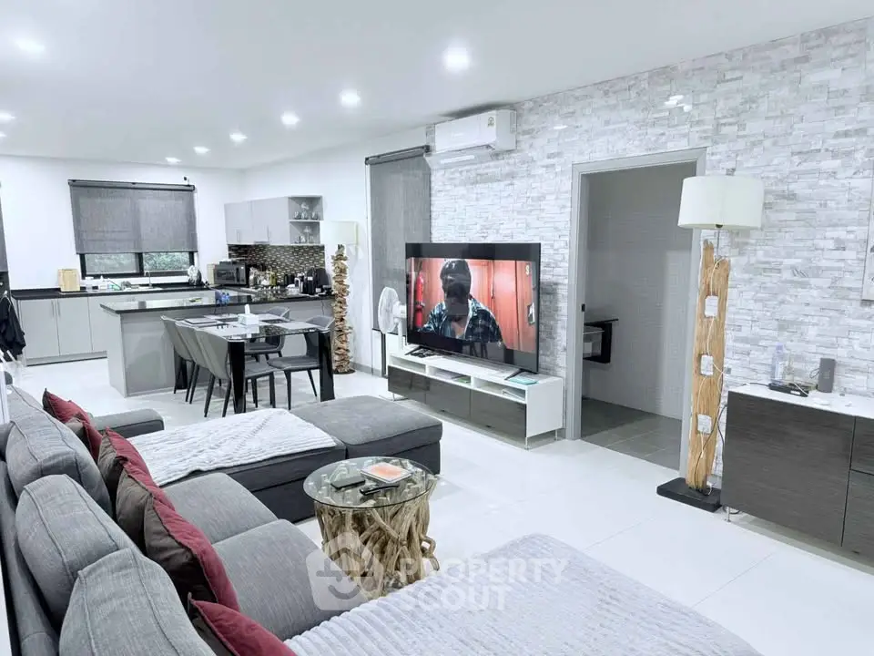 Spacious modern living room with open kitchen, stylish decor, and cozy seating area.