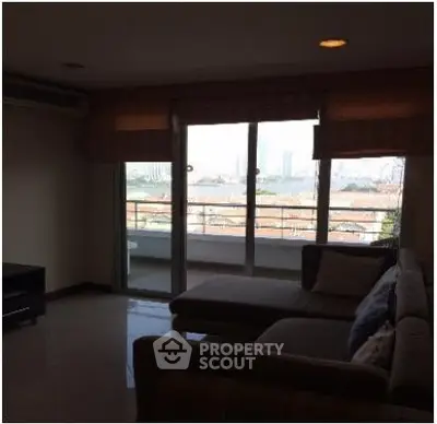 Spacious living room with large windows and city view, perfect for relaxation.