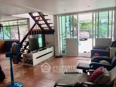 Spacious living room with modern decor and large windows overlooking a carport.