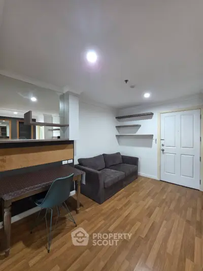 Modern living room with stylish sofa and workspace, featuring wooden flooring and ambient lighting.