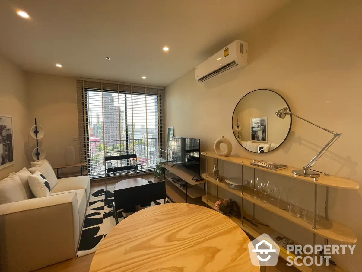 Modern living space boasting a cozy white sofa, sleek glass coffee table, and a charming dining area with city views through the balcony.