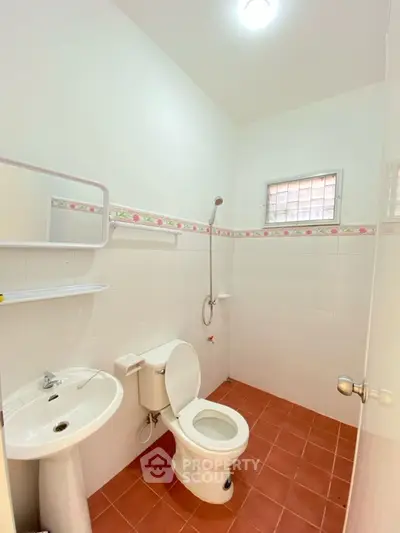Bright and clean bathroom with white tiles and terracotta floor