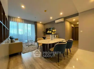 Modern living room with elegant dining area and cozy seating, featuring stylish decor and ambient lighting.