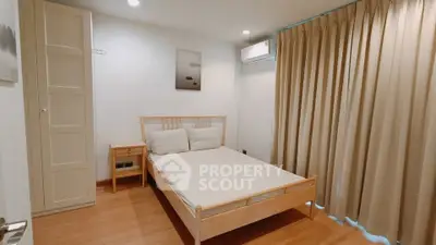 Cozy bedroom with wooden flooring and modern furnishings in a stylish apartment.