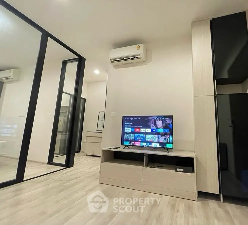 Modern living room with sleek TV setup and air conditioning in stylish apartment.