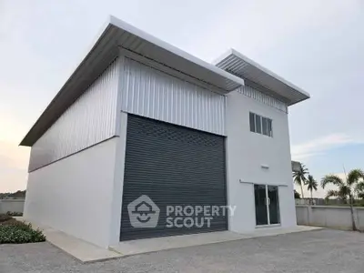 Modern industrial warehouse with sleek metal facade and large roller door.