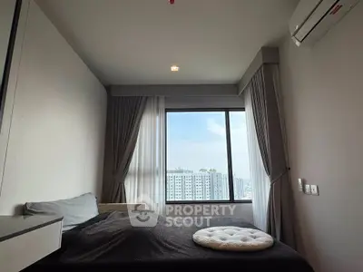 Modern bedroom with large window offering city view, featuring sleek design and cozy ambiance.