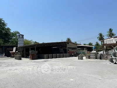 Industrial property with open warehouse and storage area under clear blue sky.