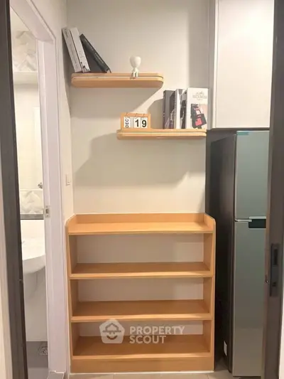 Compact storage area with wooden shelves and modern fridge in cozy apartment