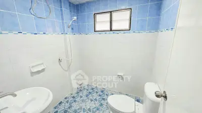 Bright and clean bathroom with blue and white tiles, featuring a shower and modern fixtures.