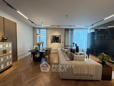 Luxurious living room with elegant dining area and modern decor, featuring herringbone wood flooring and large windows.