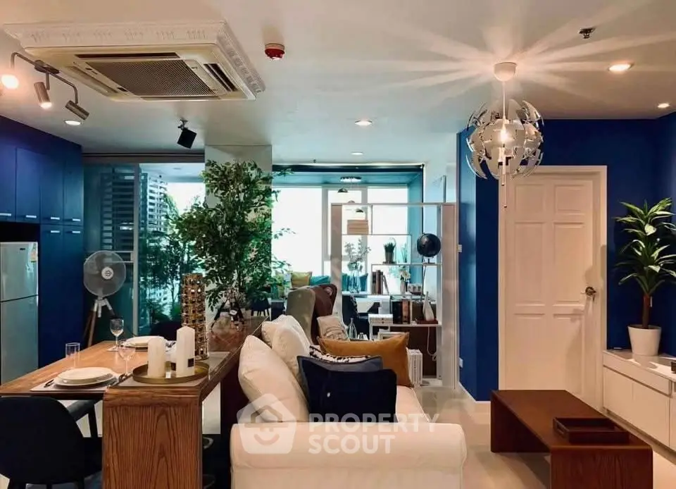 Modern living room with stylish decor and open layout, featuring blue accents and natural light.