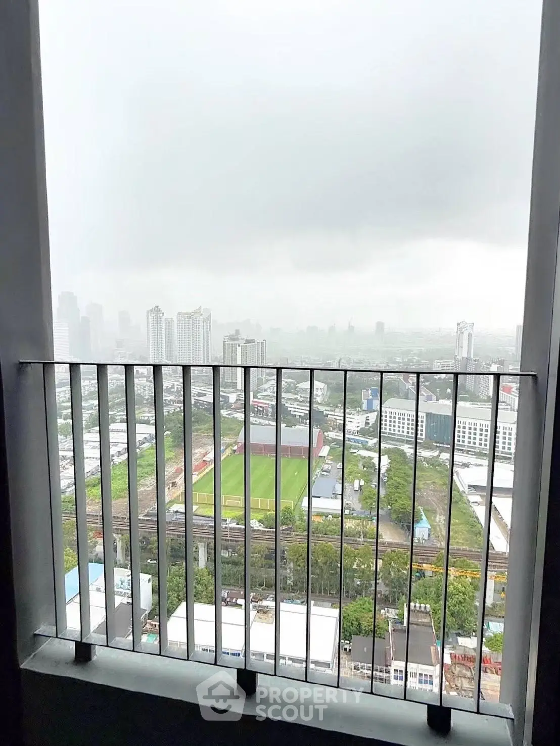 Stunning cityscape view from a high-rise balcony, showcasing urban skyline and lush greenery.