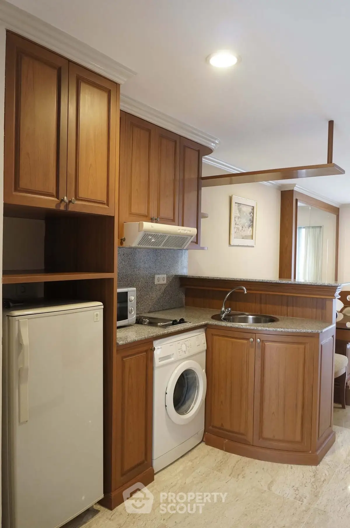 Charming compact kitchen with wooden cabinets and modern appliances, perfect for cozy living spaces.