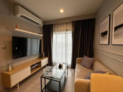 Modern living room with sleek furniture and large TV, featuring elegant decor and natural light.