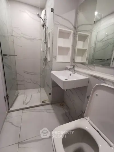 Modern bathroom with sleek marble tiles and glass shower enclosure