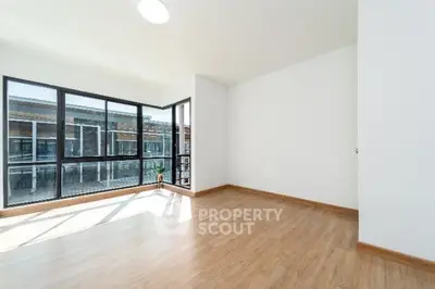 Spacious empty room with large windows and wooden flooring, ideal for customization.