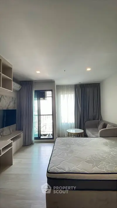 Modern studio apartment with balcony, cozy living area, and natural light.