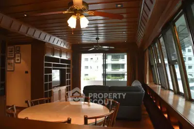 Spacious living room with wooden decor and large windows offering a bright and airy ambiance.